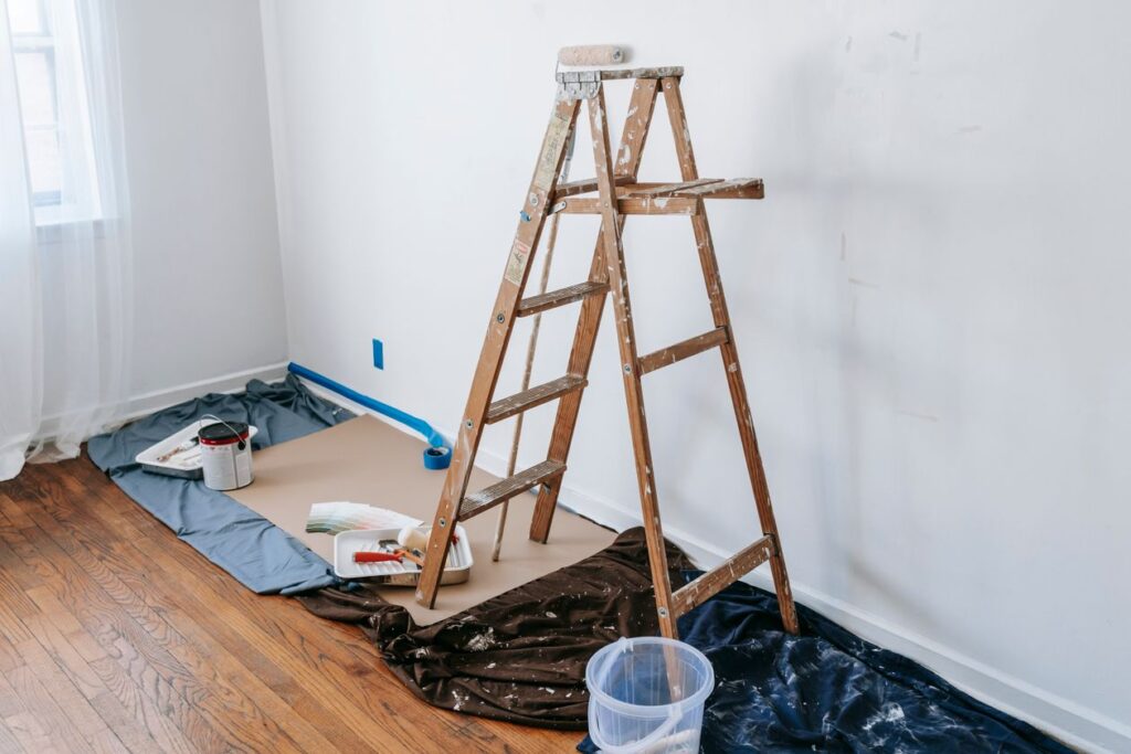 Kamer met afgedekte vloer en trapladder tijdens schilderwerk