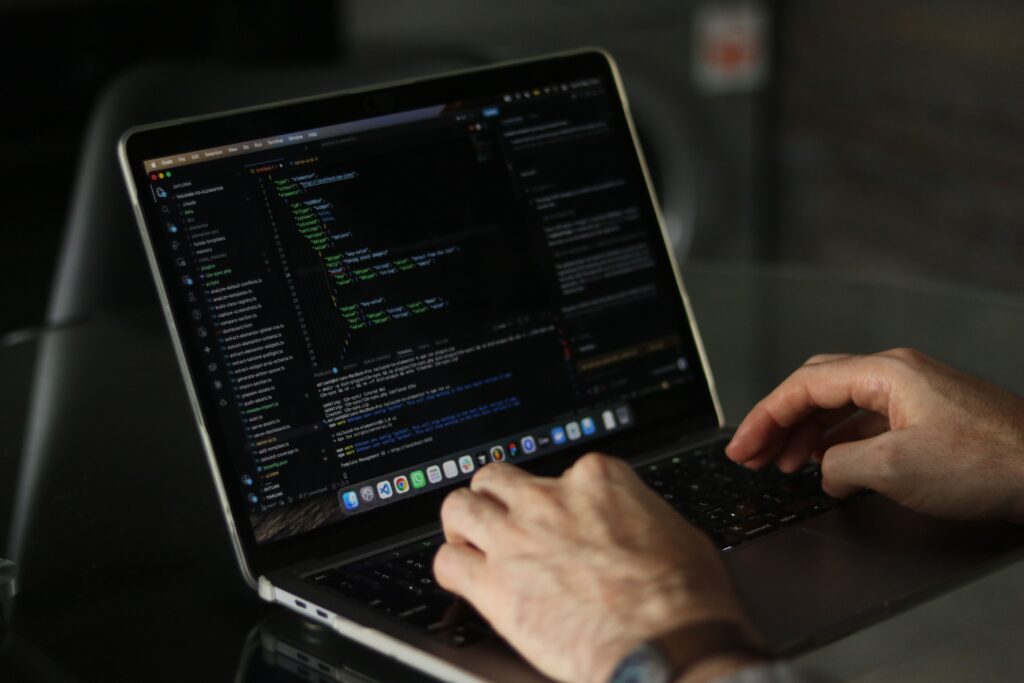 Handen typend op laptop met programmeercode