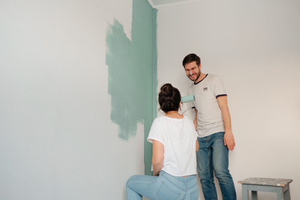Koppel schildert lachend samen een muur, symbool voor een nieuw begin