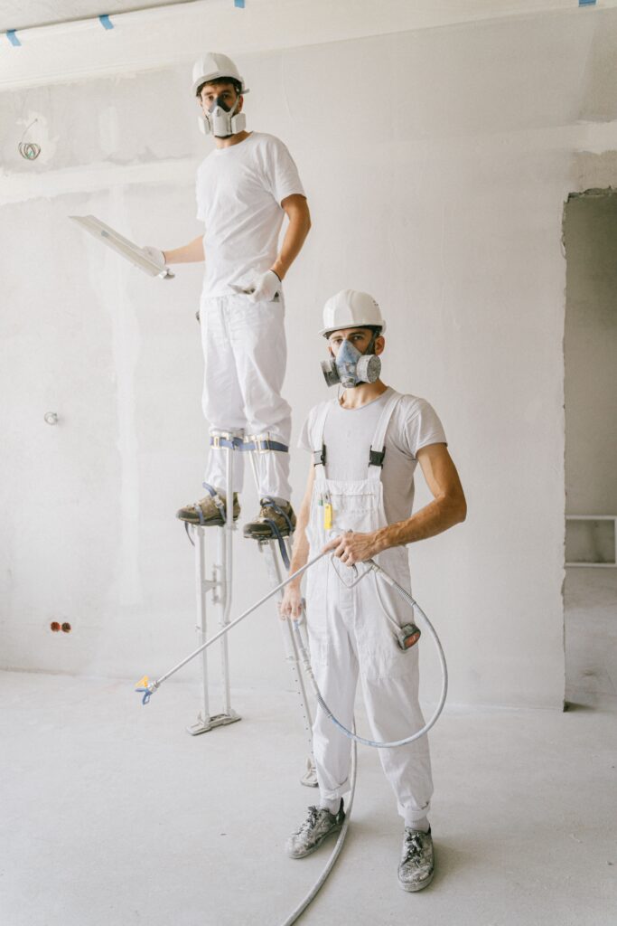 Twee schilders werken samen aan een muur op de werkvloer